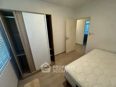 Cozy bedroom with wooden flooring, wardrobe, and comfortable mattress, perfect for restful nights.