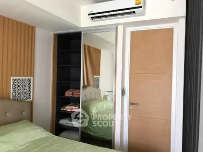 Modern bedroom with mirrored wardrobe and air conditioning unit, featuring sleek wooden accents.