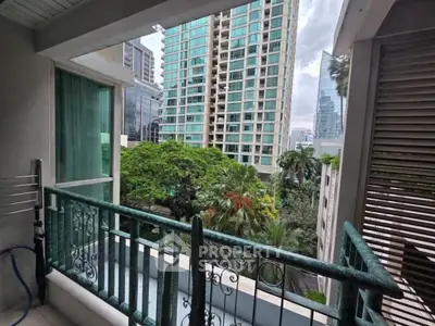 Charming balcony view overlooking lush greenery and modern high-rise buildings in urban setting.