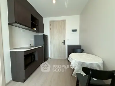 Modern compact kitchen with dark wood cabinets and dining area in a cozy apartment.