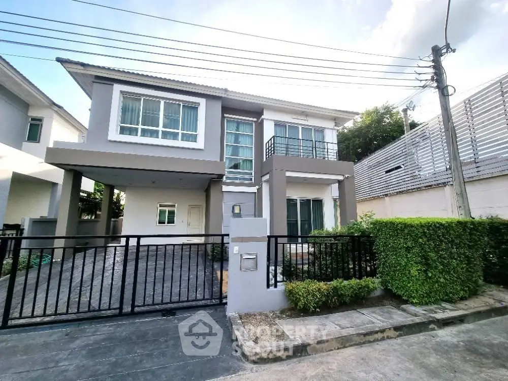Modern two-story house with gated driveway and lush greenery