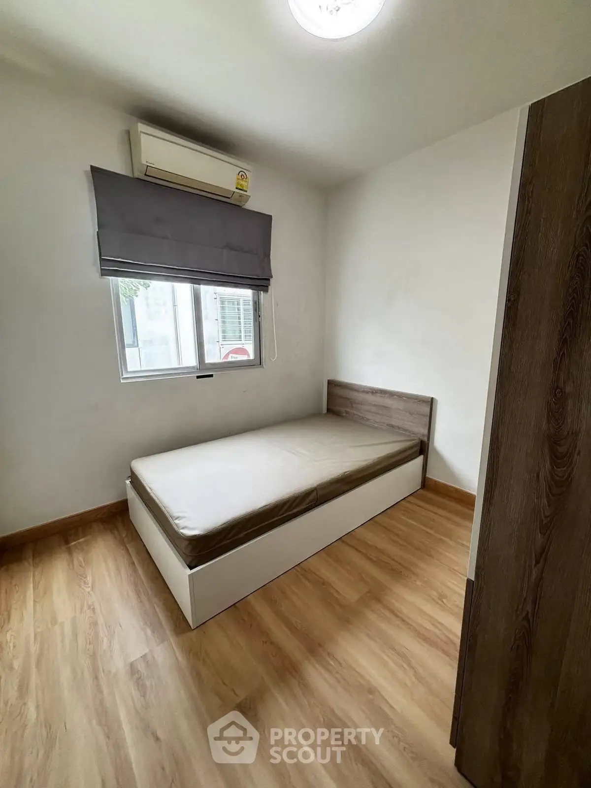 Cozy minimalist bedroom with wooden flooring and natural light