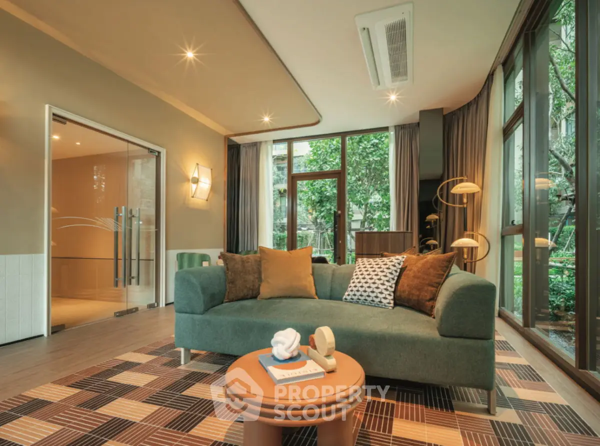 Spacious living room with modern decor and large windows overlooking greenery.