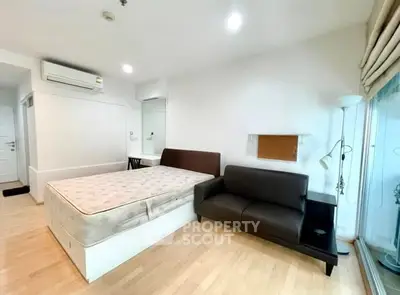 Modern studio apartment with bed, sofa, and natural light