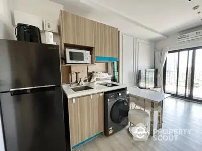 Modern kitchen with sleek appliances and open layout, featuring a washing machine and large windows for natural light.