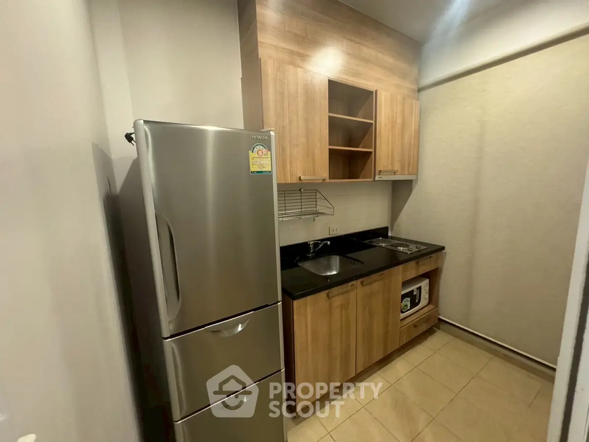 Compact modern kitchen with stainless steel fridge and wooden cabinets