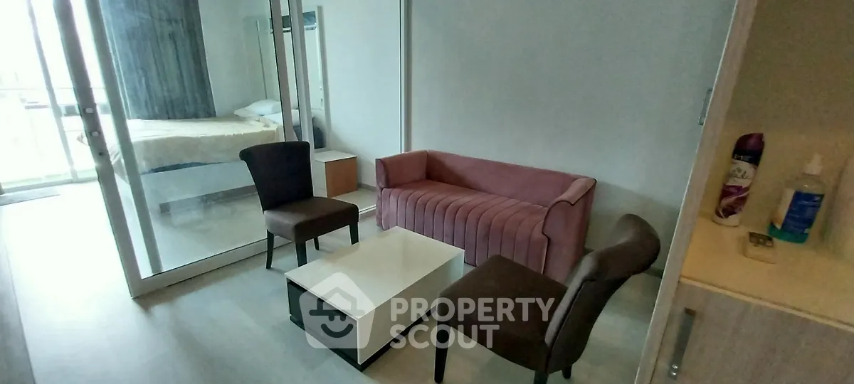 Modern living room with pink sofa and glass partition leading to bedroom