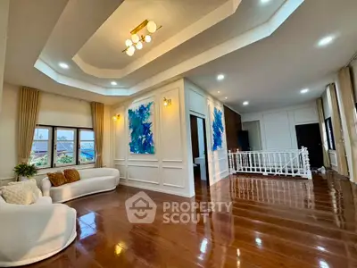 Spacious living room with elegant wooden flooring and modern lighting, featuring large windows and stylish decor.