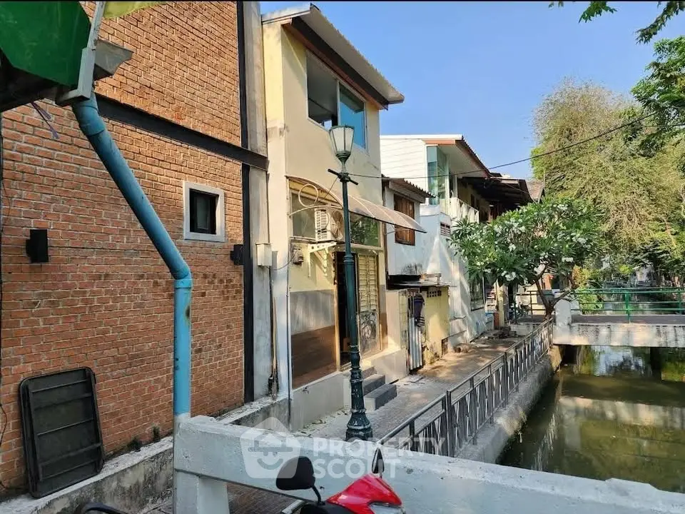Charming canal-side residential building with brick facade and lush greenery.