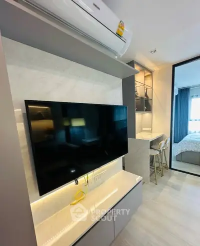 Modern living room with sleek TV setup and stylish bar stools in a contemporary apartment.