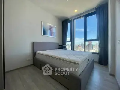 Modern bedroom with large windows offering stunning city views, featuring a comfortable bed and minimalist decor.