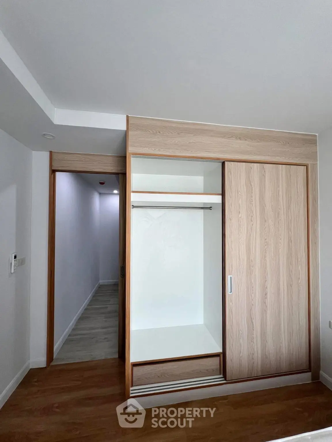 Spacious bedroom with built-in wooden wardrobe and sleek flooring