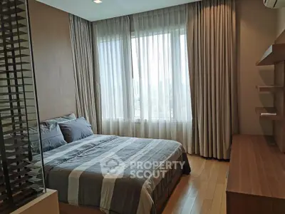 Modern bedroom with large window and stylish decor in a high-rise apartment.