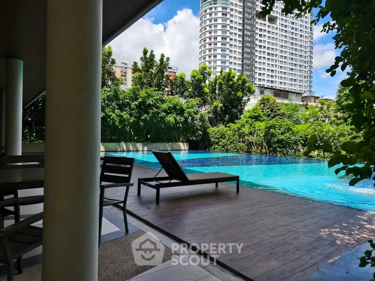 Luxurious poolside view with modern high-rise building backdrop, perfect for relaxation and leisure.