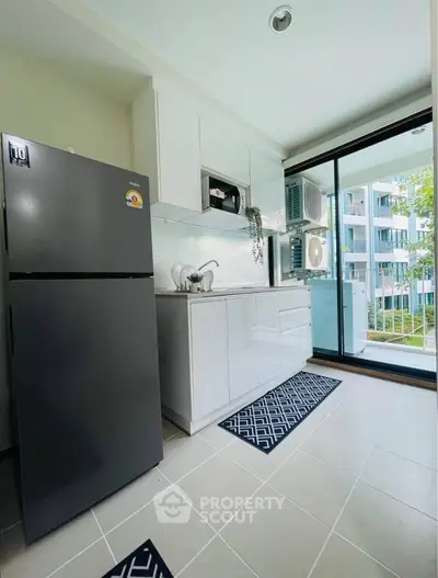 Modern kitchen with sleek appliances and balcony view in contemporary apartment.