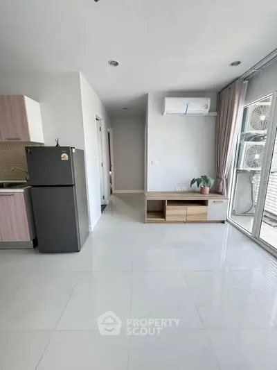 Modern apartment interior with sleek kitchen and spacious living area, featuring large windows and natural light.