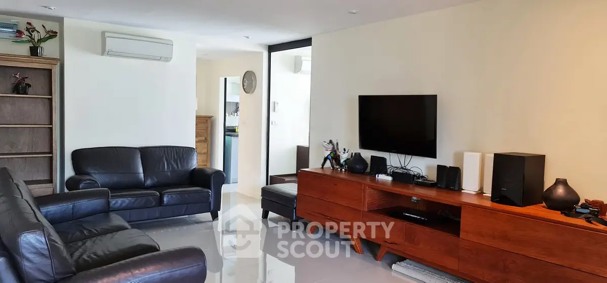 Spacious living room with modern leather sofas and sleek wooden TV console
