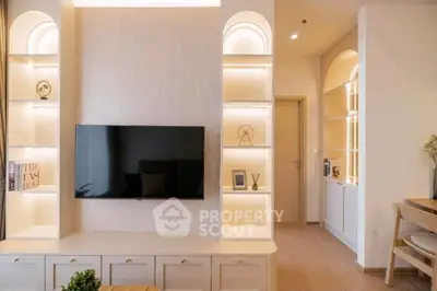 Modern living room with built-in shelves and wall-mounted TV, featuring elegant lighting and wooden flooring.