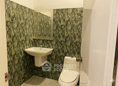 Modern bathroom with unique green camouflage tile design and sleek fixtures.