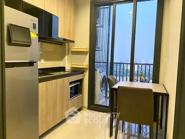 Modern kitchen with balcony view, featuring sleek appliances and compact dining area.