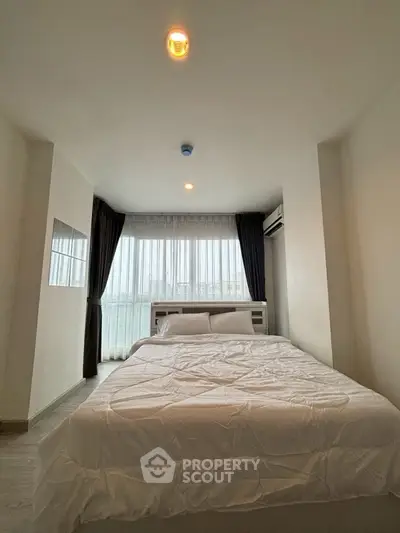 Cozy bedroom with large window and modern decor in a stylish apartment.