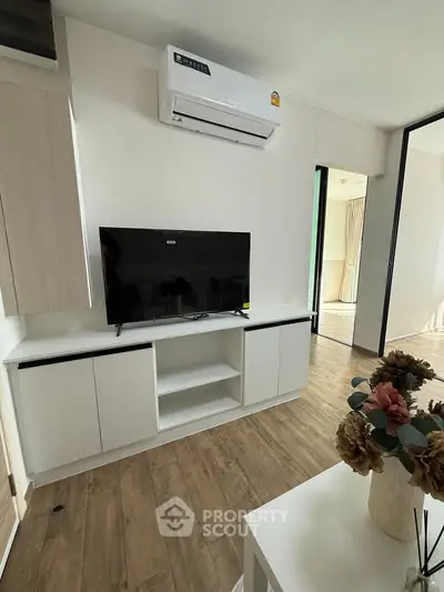 Modern living room with sleek TV unit and air conditioning, featuring elegant wooden flooring and stylish decor.