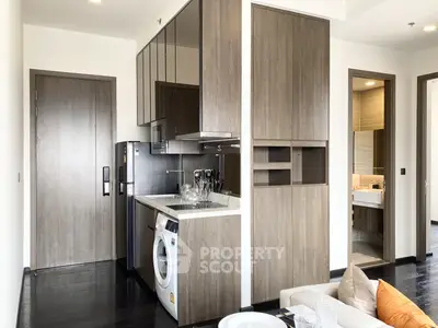 Modern compact kitchen with integrated appliances and wooden cabinetry, seamlessly blending with a cozy living space, perfect for urban living.