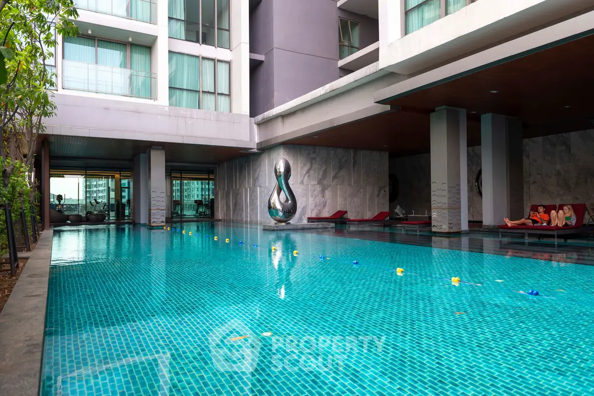 Luxurious condominium pool area with modern design and relaxing lounge chairs.