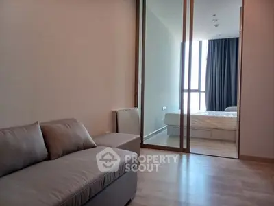Modern apartment with cozy living room and bedroom separated by glass partition.