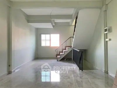 Spacious interior with modern staircase and large window, ideal for customization.