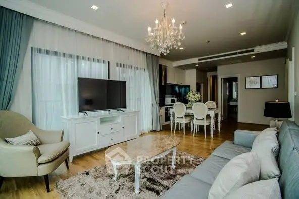 Elegant living room with chandelier, plush sofa, and modern TV setup in a cozy apartment.