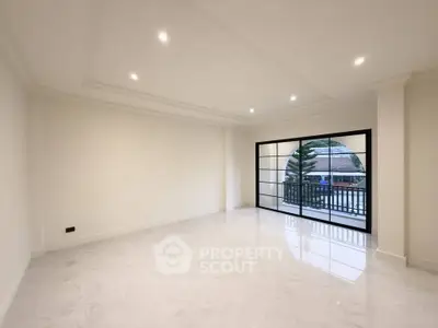 Spacious modern living room with large windows and balcony access, featuring elegant marble flooring.