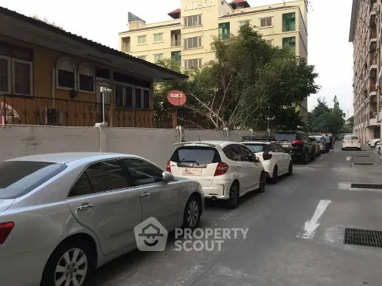 Urban residential street with parked cars and apartment buildings.