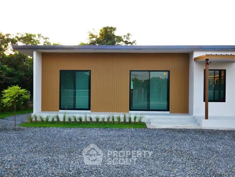 Modern single-story house with large windows and gravel driveway