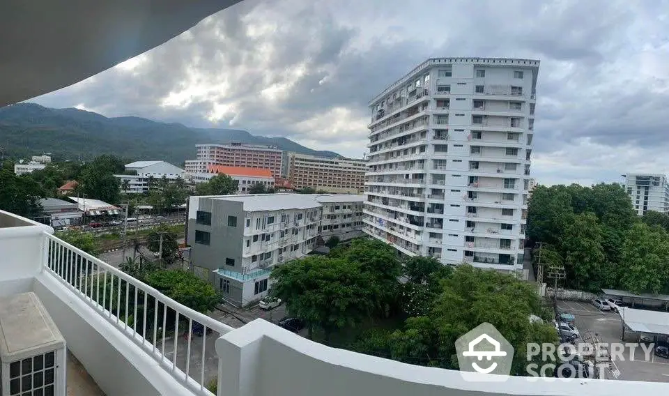 Panoramic view of modern apartment buildings with lush greenery and mountains in the background.