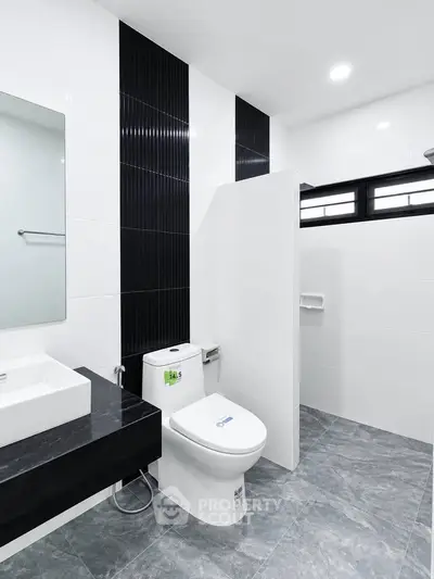 Modern bathroom with sleek black and white design, featuring a toilet and stylish sink.