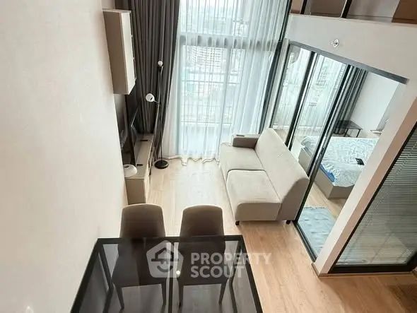 Modern loft apartment with high ceilings and large windows offering city views.