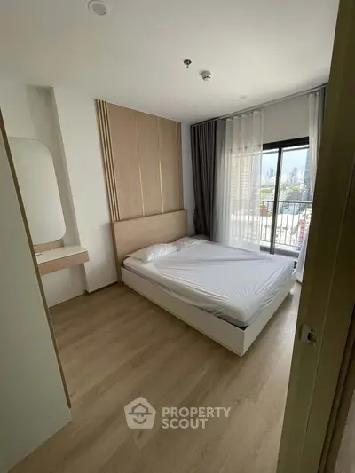 Modern bedroom with large window and city view, featuring minimalist design and wooden flooring.