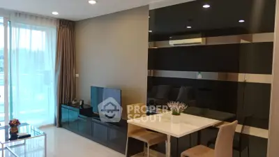 Modern living room with sleek design, featuring a TV, dining area, and large windows for natural light.