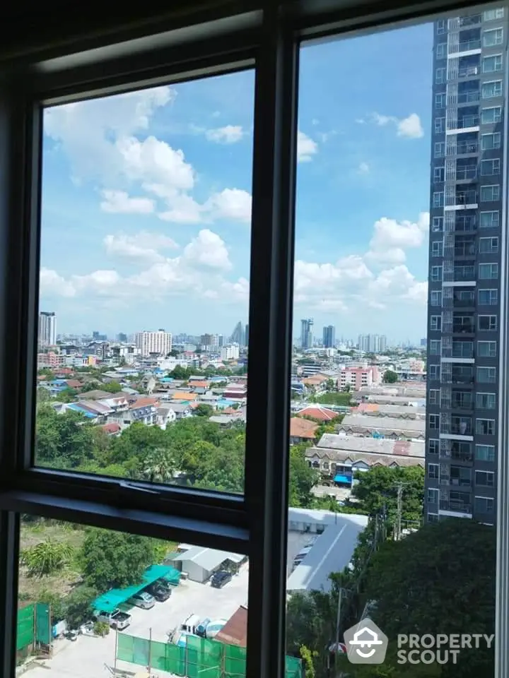 Stunning cityscape view from high-rise apartment window with clear blue sky.