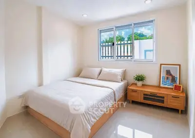 Bright and cozy bedroom with modern decor and large window view.