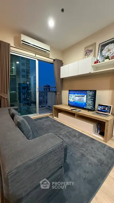 Modern living room with cozy sofa, large TV, and balcony view in a stylish apartment.