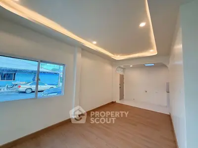 Spacious modern living room with recessed lighting and large window view.