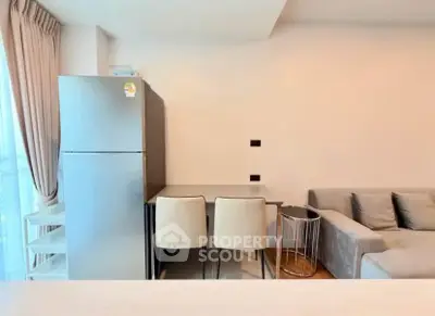 Modern living room with sleek fridge and cozy seating area, perfect for urban living.