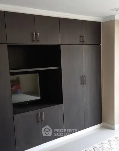 Modern bedroom with sleek built-in dark wood wardrobe and TV space