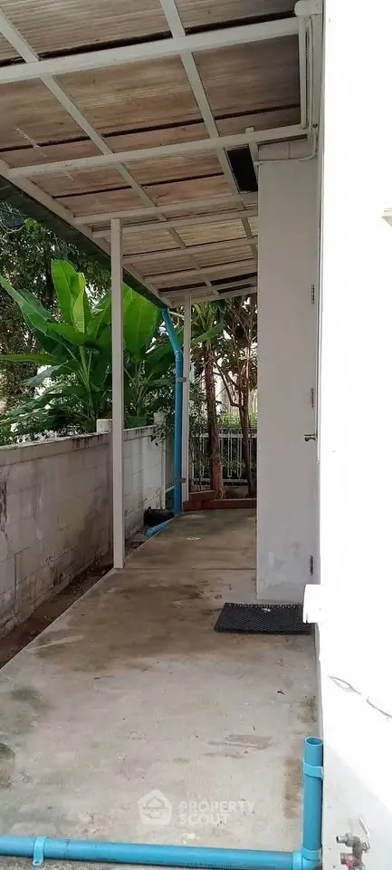 Covered outdoor walkway with garden view and concrete flooring