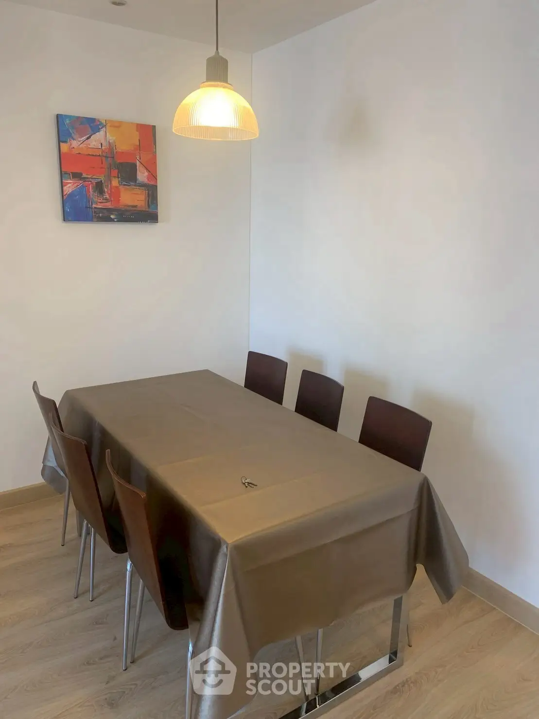 Modern dining area with stylish table and chairs, featuring contemporary artwork and pendant lighting.