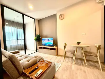 Modern living room with cozy sofa and TV, adjacent to a dining area with natural light.