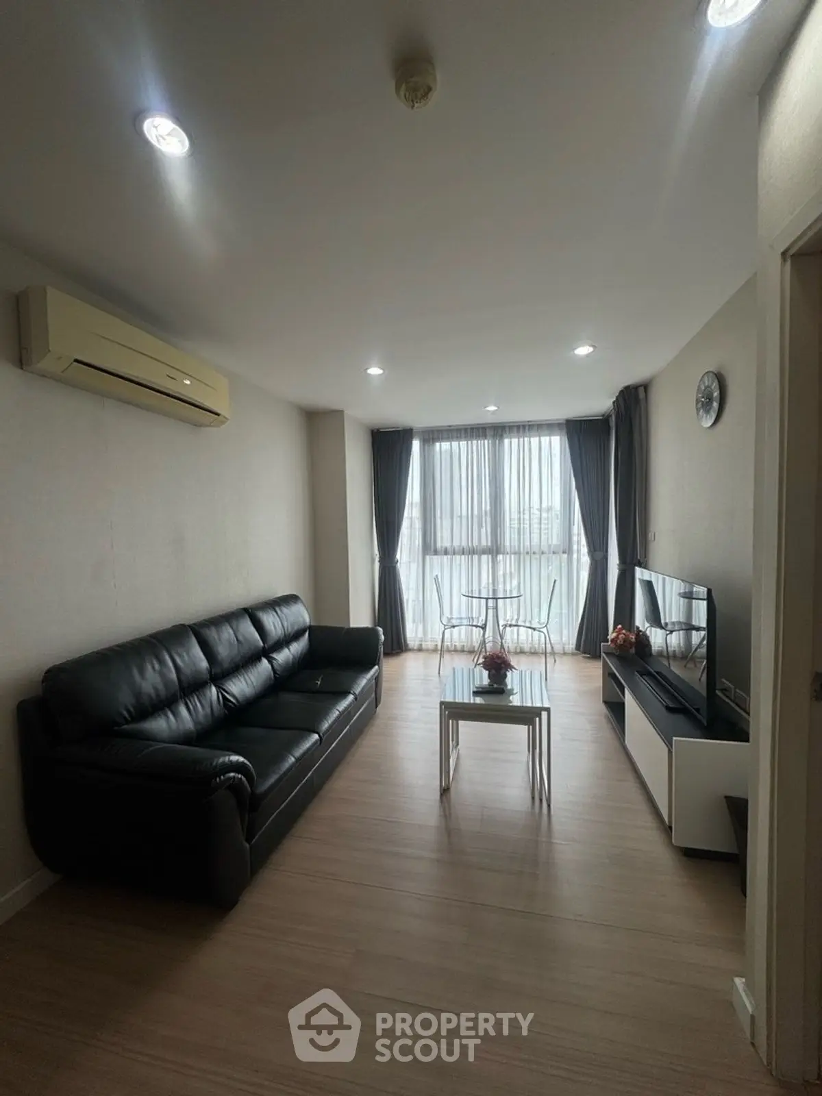 Modern living room with sleek black leather sofa and large window view