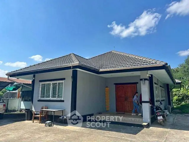 Charming single-story home with tiled roof and spacious driveway under clear blue sky.
